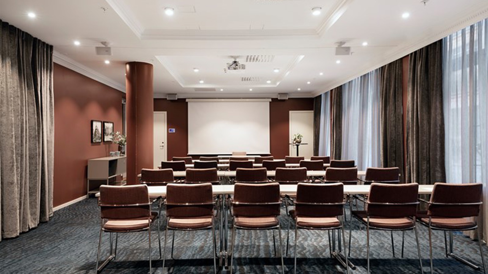 Konferensrum med skolsittning, grått golv, bruna väggar