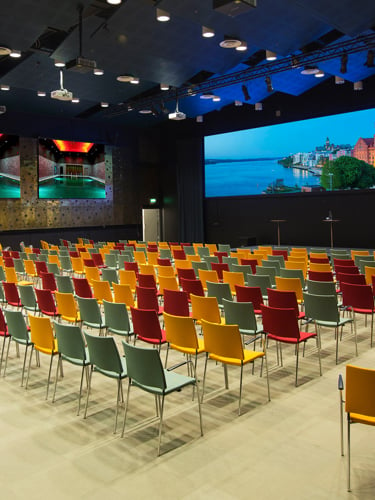 Large venue with arranged chairs and projector