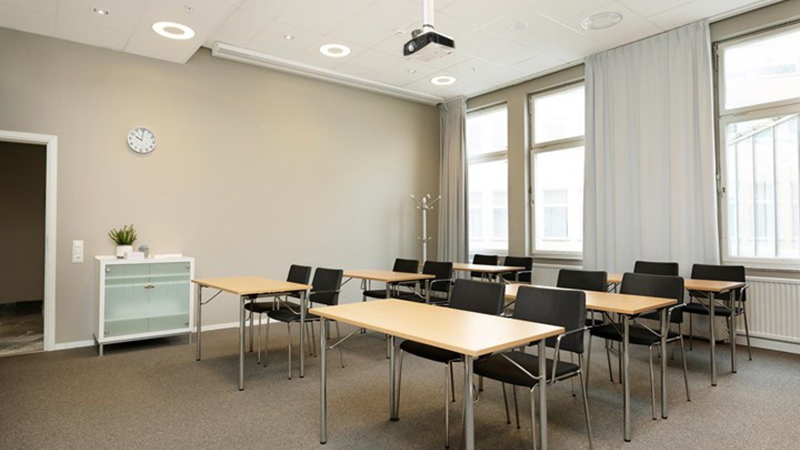 Konferensrum med skolsittning, stora fönster, brun matta, träbord