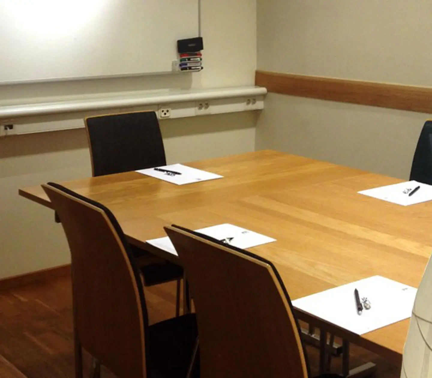 Smaller group room with white walls, wooden floor and wooden furniture