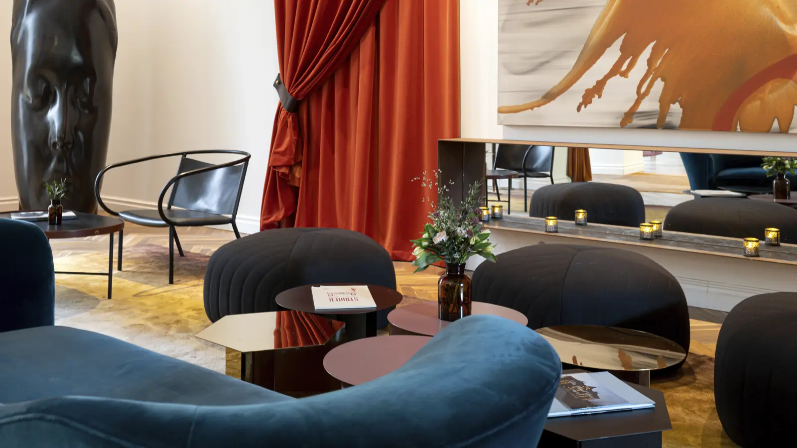 Elegant room with rich red drapes, modern abstract artwork, and stylish seating arrangement in a luxurious interior setting.