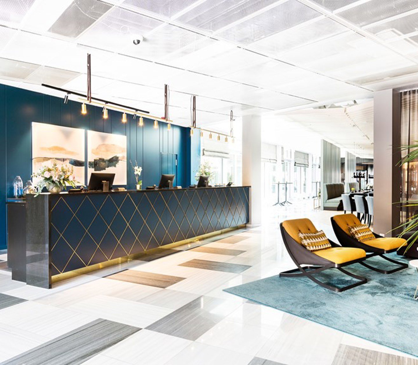 Svart reception med gulddetaljer, blå fondvägg, svart- och vitmönstrat golv