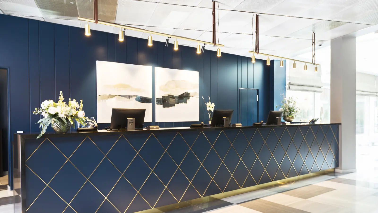 Black reception with gold details, blue wall, black and white patterned floor