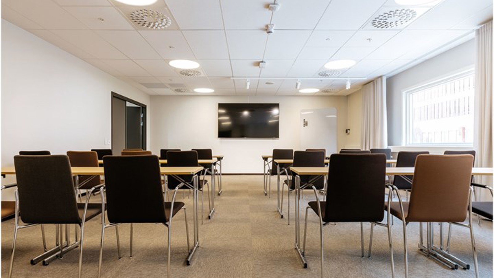 Conference room with school seating, white walls and brown carpet