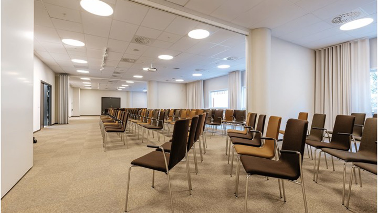Conference room with cinema seating, brown chairs and large windows