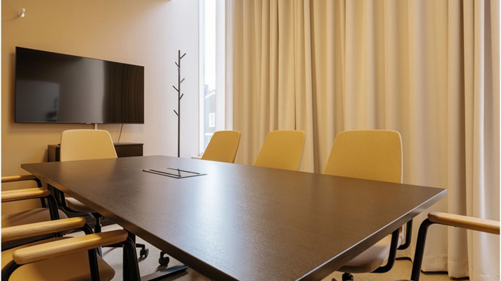 Conference room with board seating in yellow tones and brown table