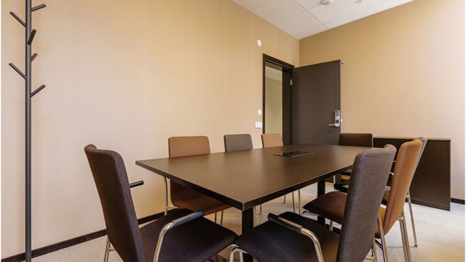 Konferensrum med bruna bord och stolar i styrelsesittning