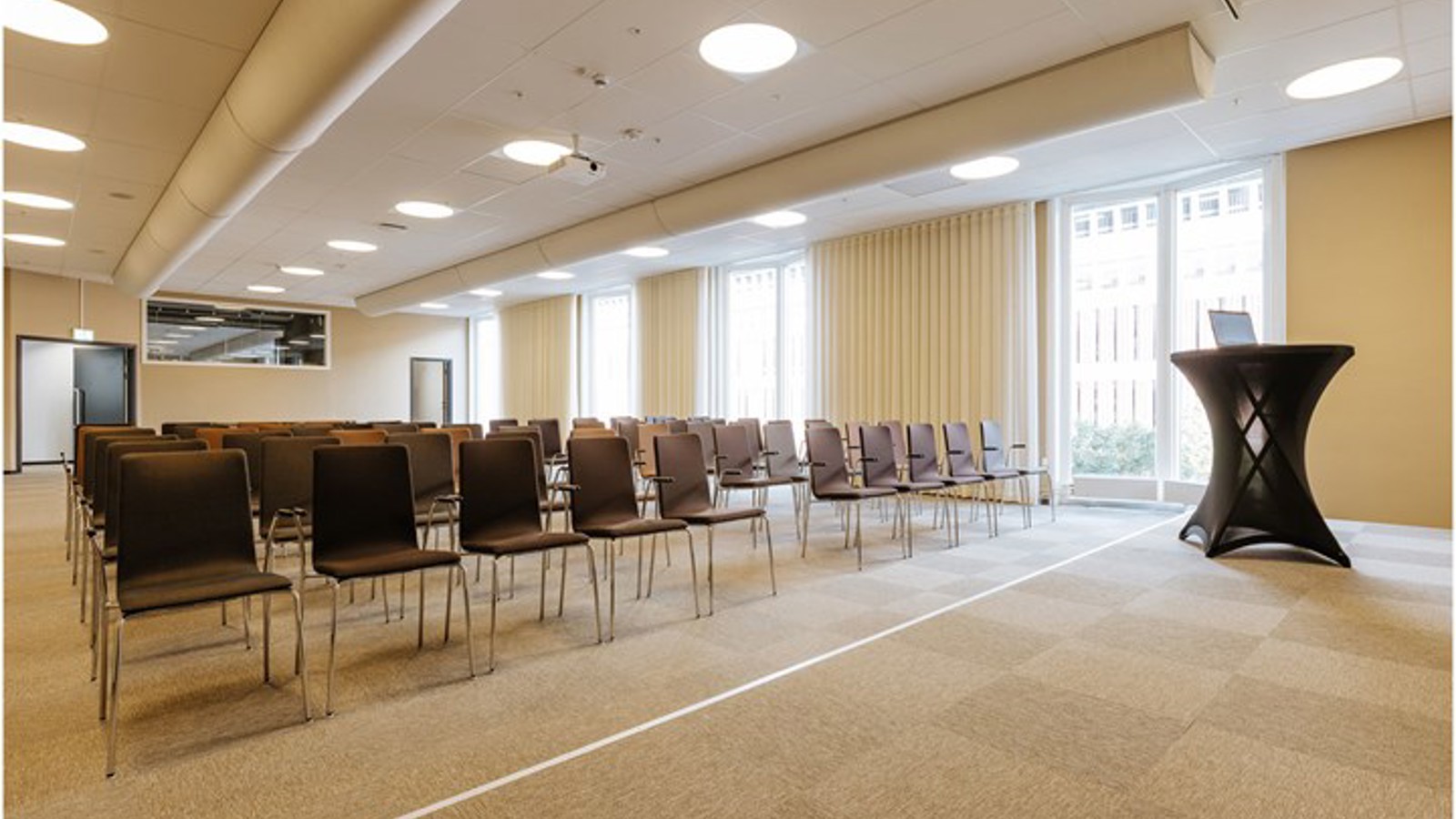 Konferenslokal med biosittning, scen och stora fönster