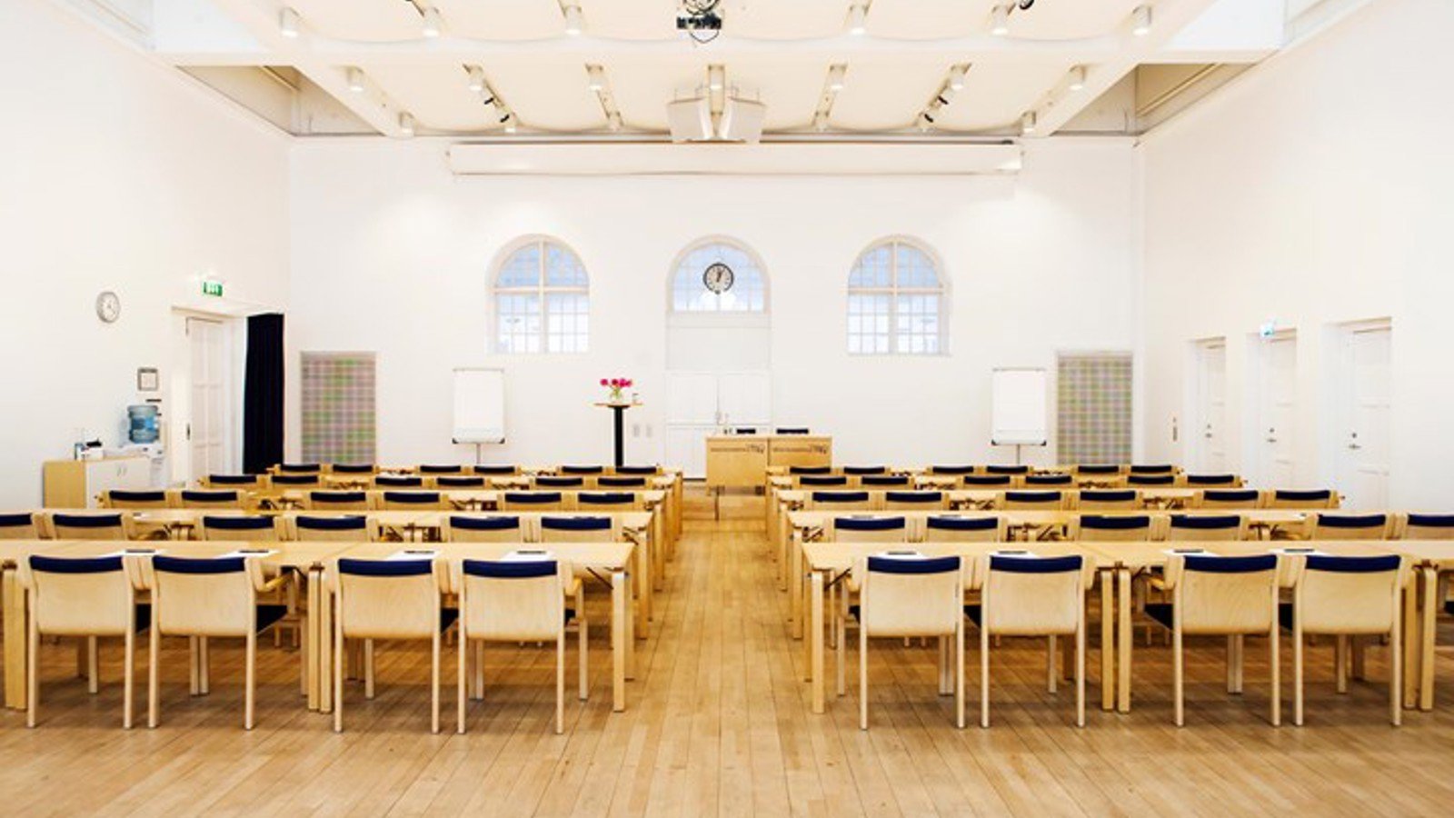 Konferenssal med biosittning, stolar i trä, trägolv och vita väggar