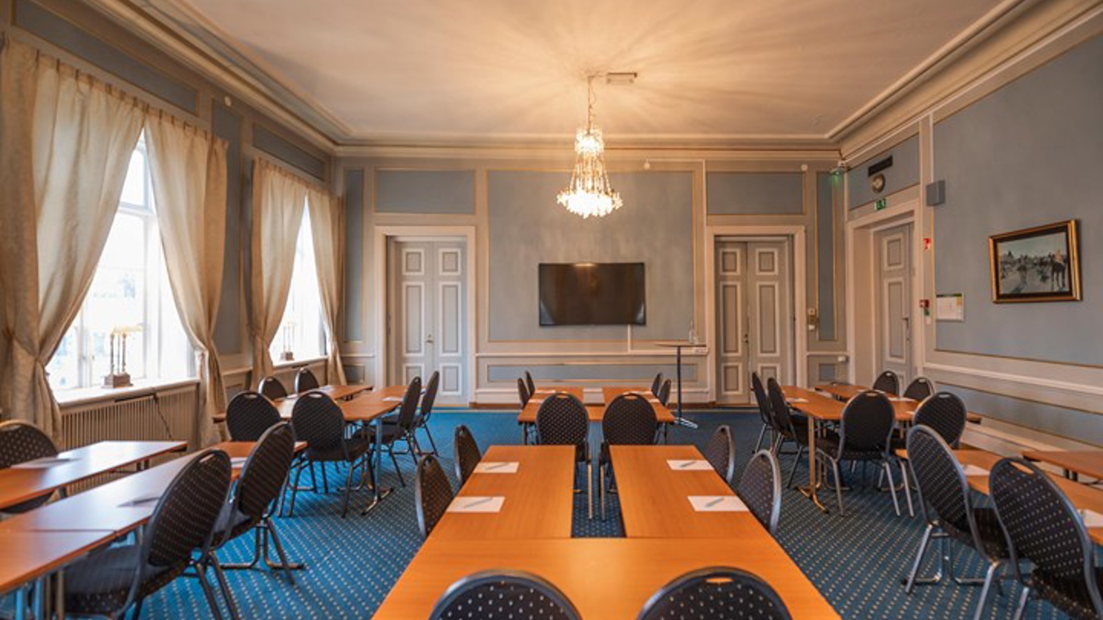 Blått konferensrum med ö-sittning, stora fönster och träbord