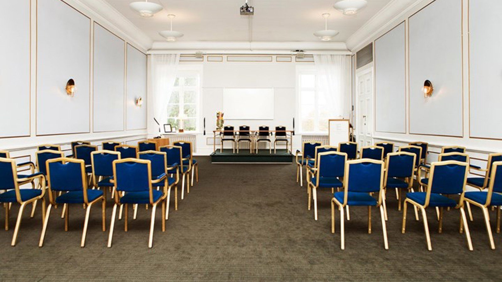 Konferenslokal med biosittning, ljusblå väggar och blå stolar