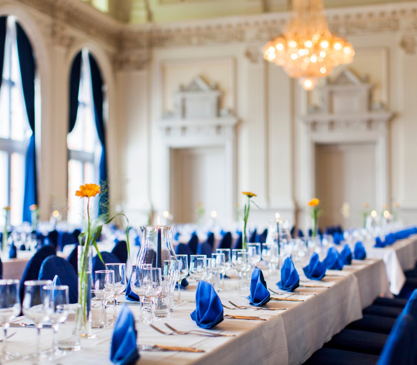 Långbord i bröllopslokal dekorerat med blå servetter