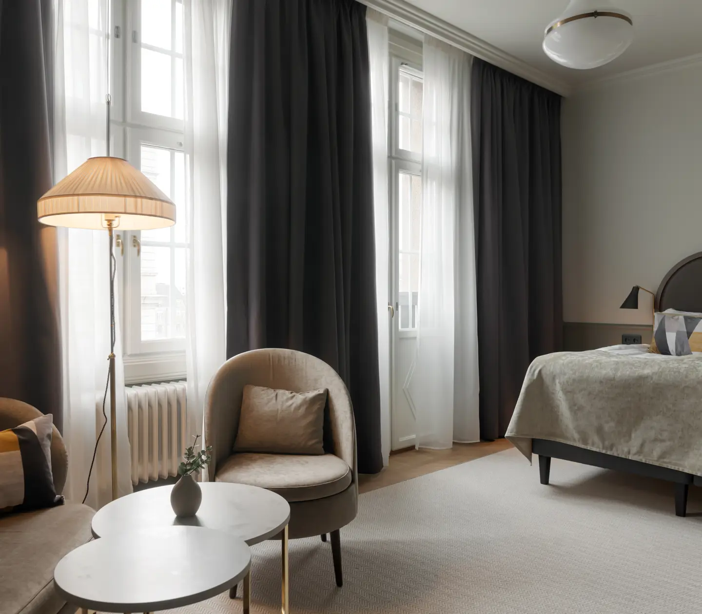 Hotellsvit med mysig sittgrupp och säng i samma rum