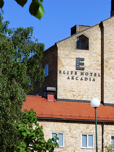 En äldre stenbyggnad med en fasadskylt där det står Elite Hotel Arcadia
