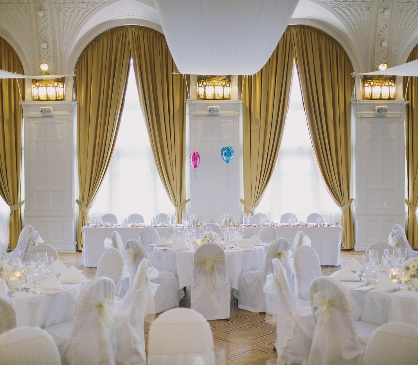 Pampig bröllopslokal med stora fönster och guldgula gardiner