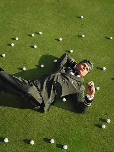 Person i uniform går på en golfbana med en golfbag över axeln.