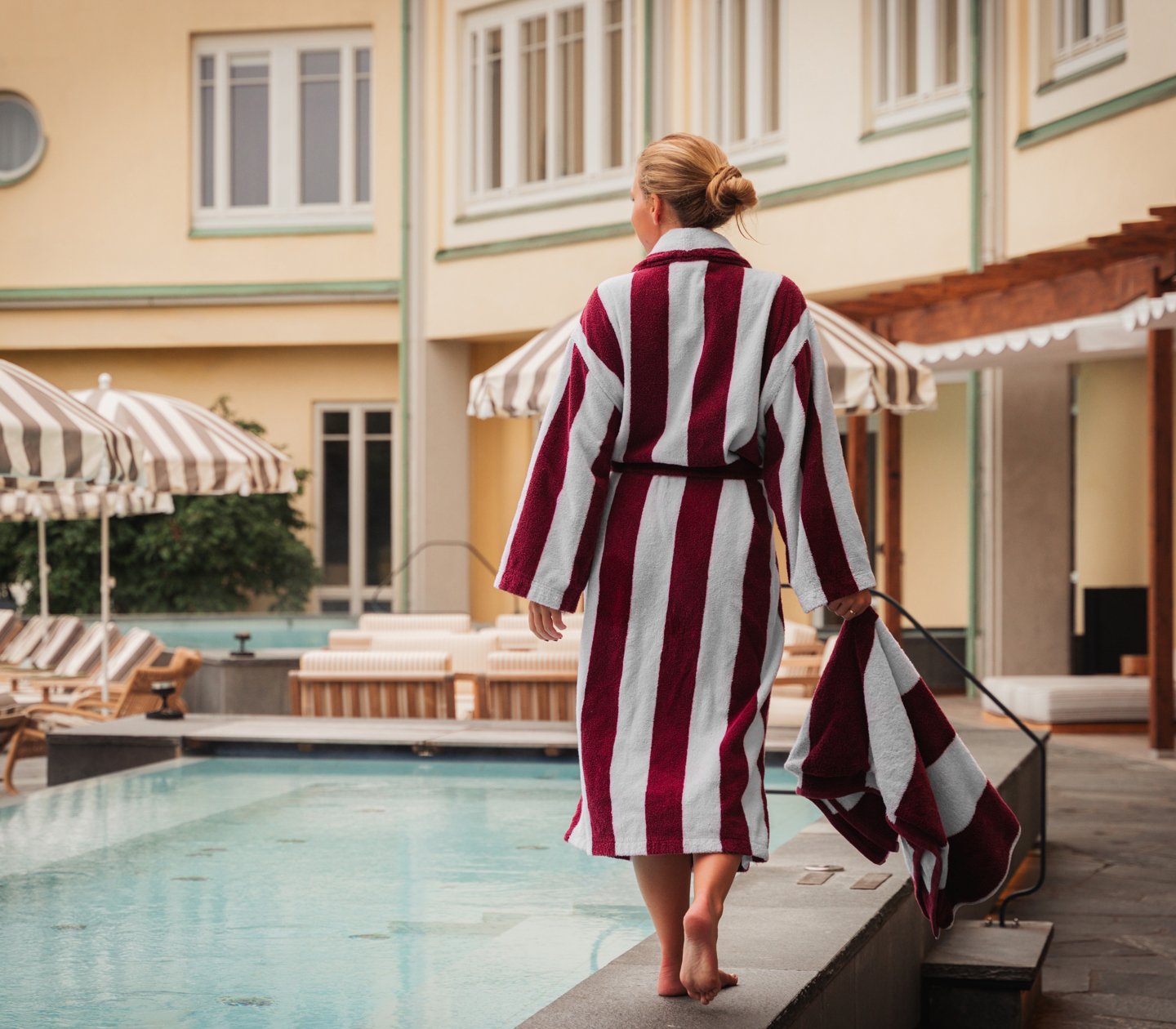 Woman in striped bathrobe walking on pool edge