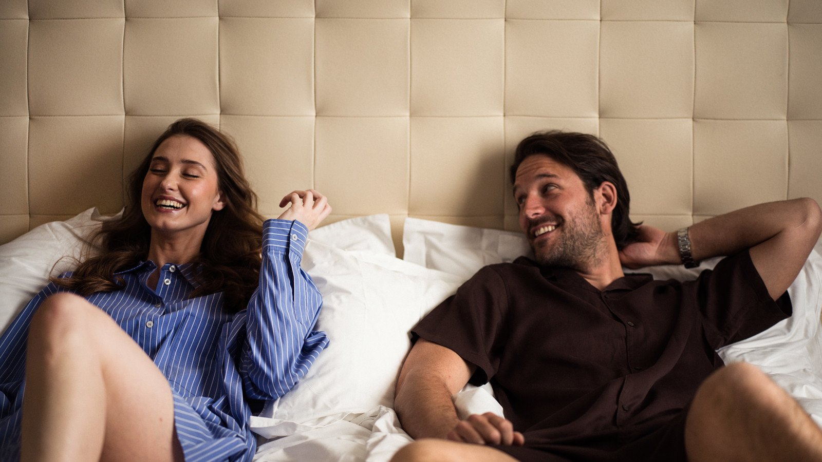 Laughing women and man in hotel bed