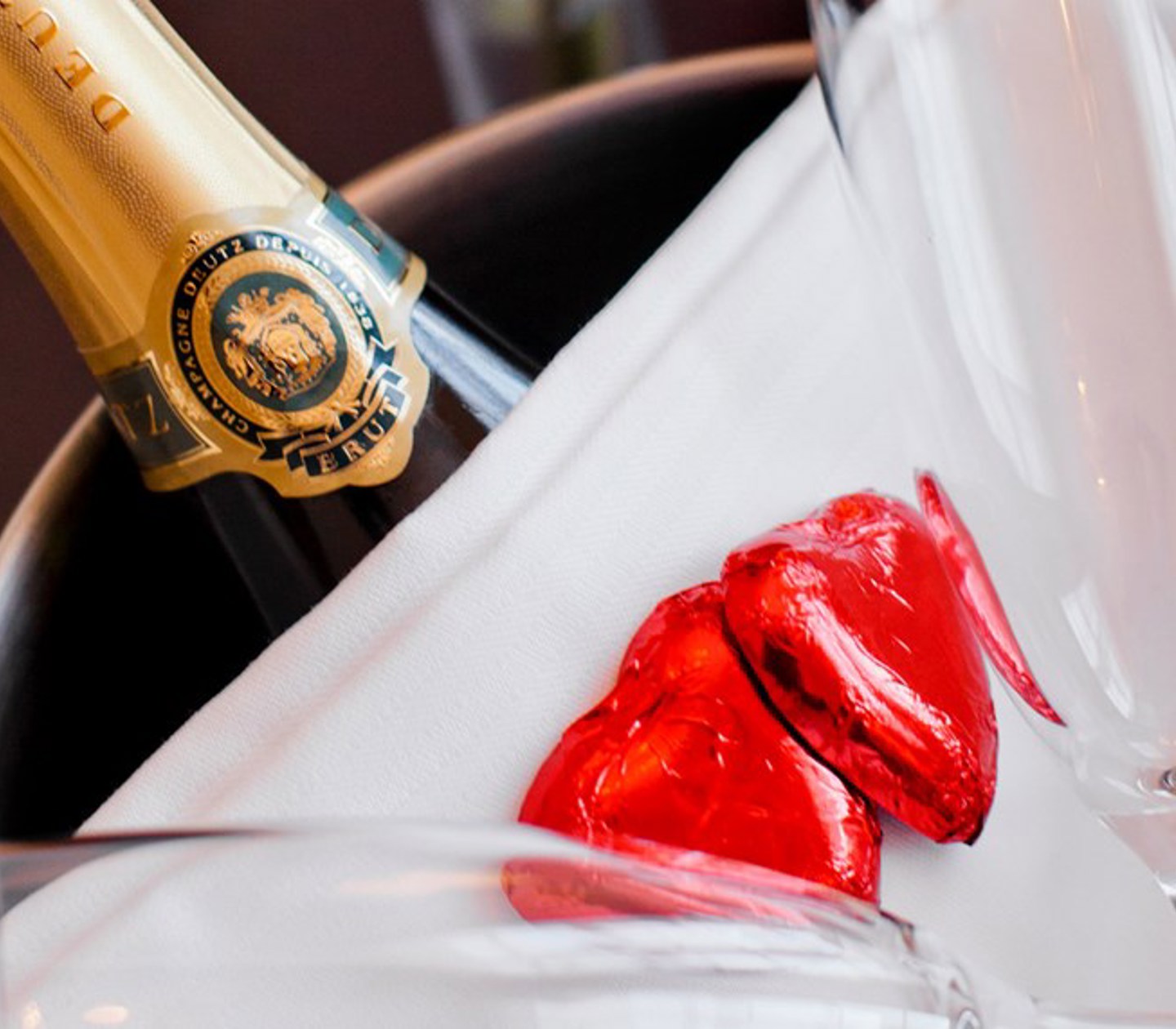 Champagneflaska i hink med röda hjärtan som dekoration.