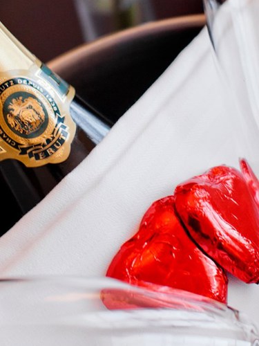 Champagneflaska i hink med röda hjärtan som dekoration.