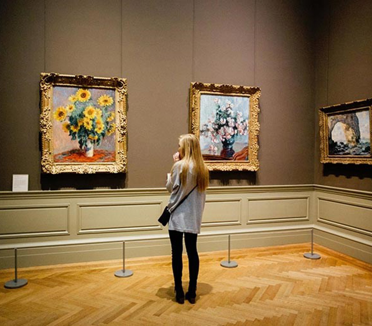 En tjej i ett museum står och tittar förundrat på tavlor. 