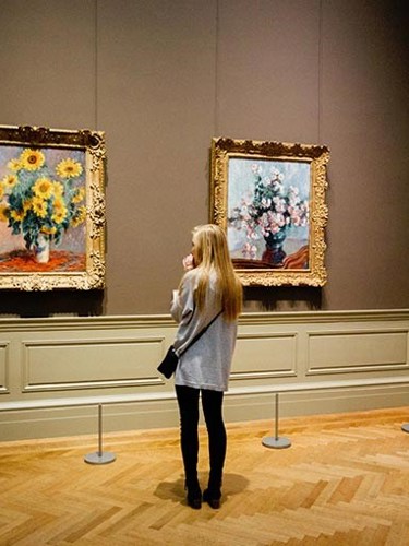 En tjej i ett museum står och tittar förundrat på tavlor. 