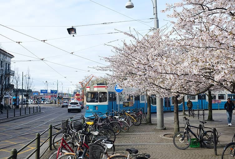 En spårvagn åker genom Göteborgs stad där många cyklar även står parkerade längs sidorna.