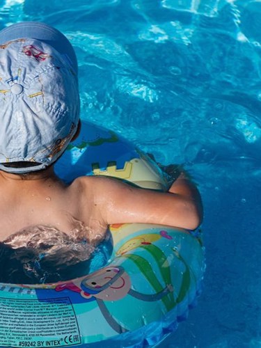 Ett barn simmar med en badring i en pool