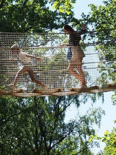 Barn går över en hängbro som finns på Skånes djurpark.