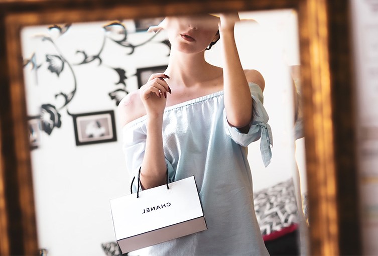 Kvinna framför spegel med Chanel-påse i handen