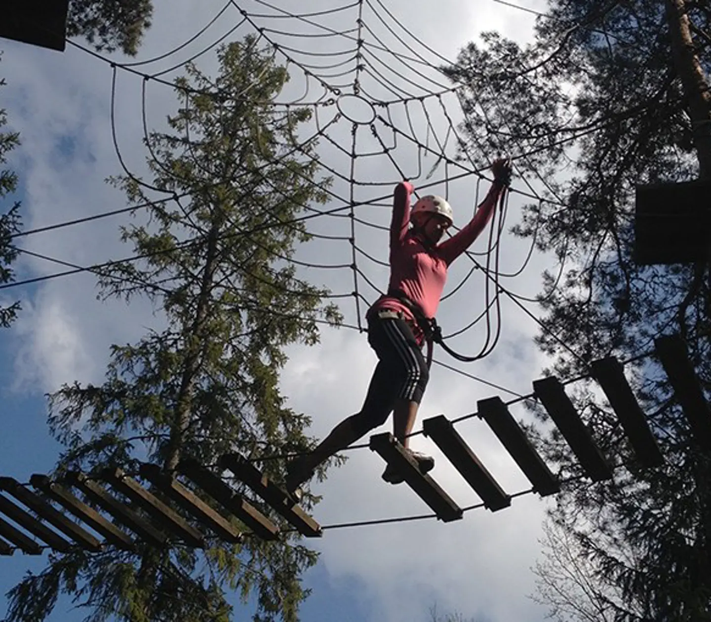Kvinna på äventyrsbana bland träd