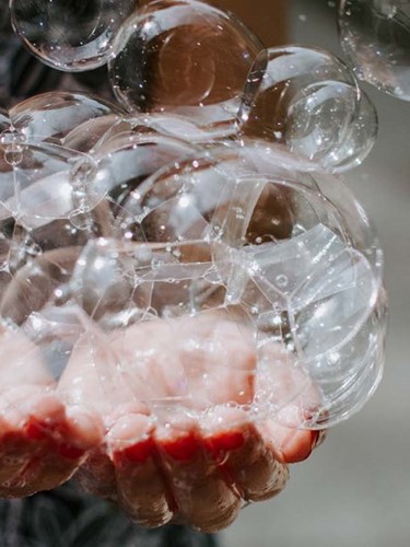 Händer som fångar såpbubblor 