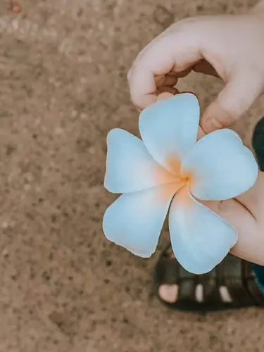 Barn med vit blomma i handen