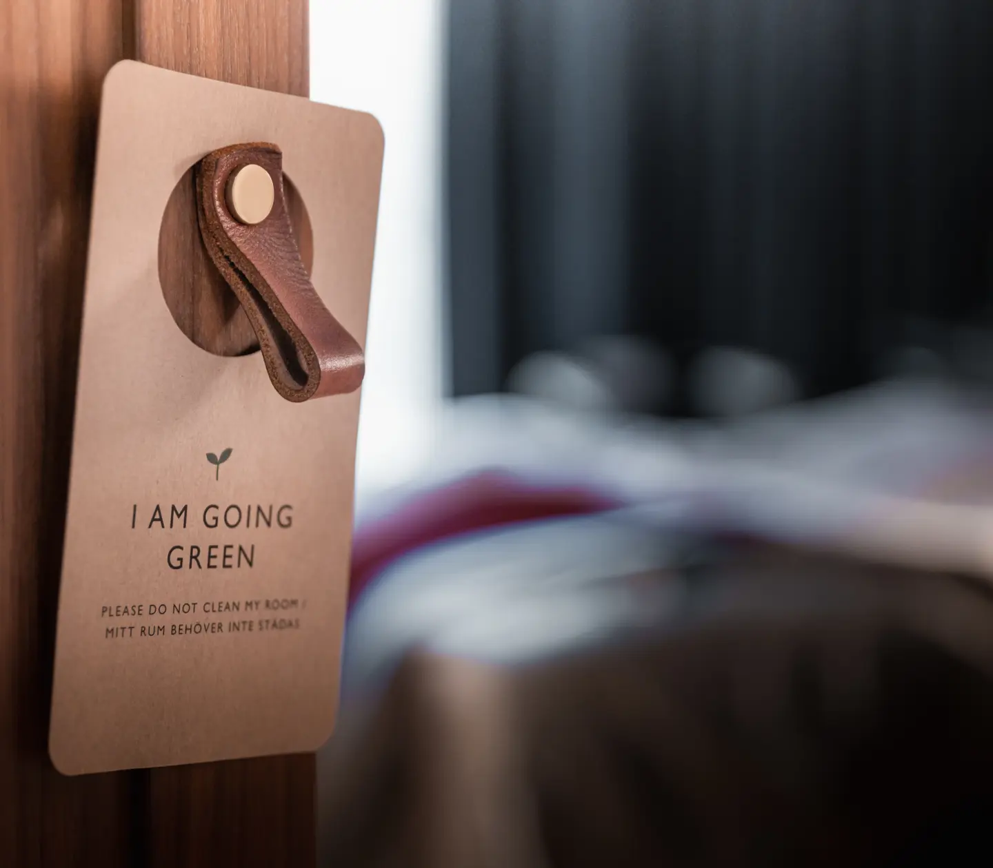 Miljöskylt upphängd på dörr med hotellrum i bakgrunden