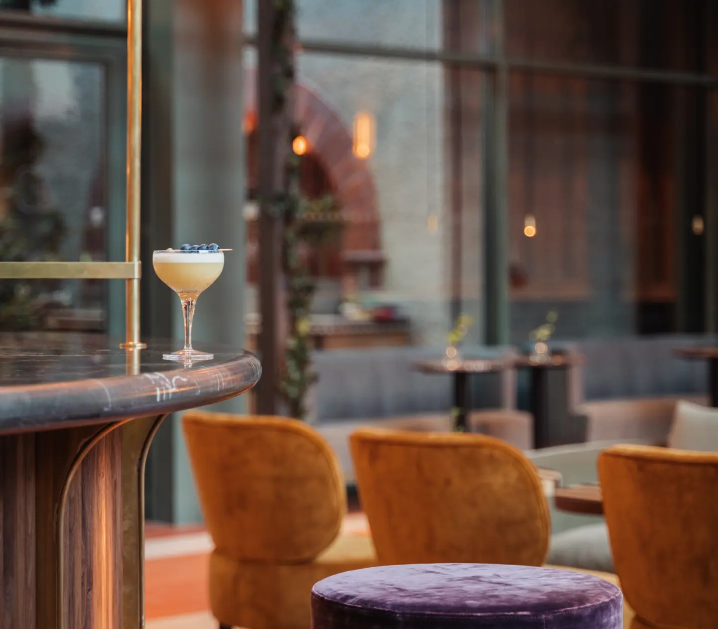 Barmiljö med ljus drink på bardisk och orange stolar i bakgrunden