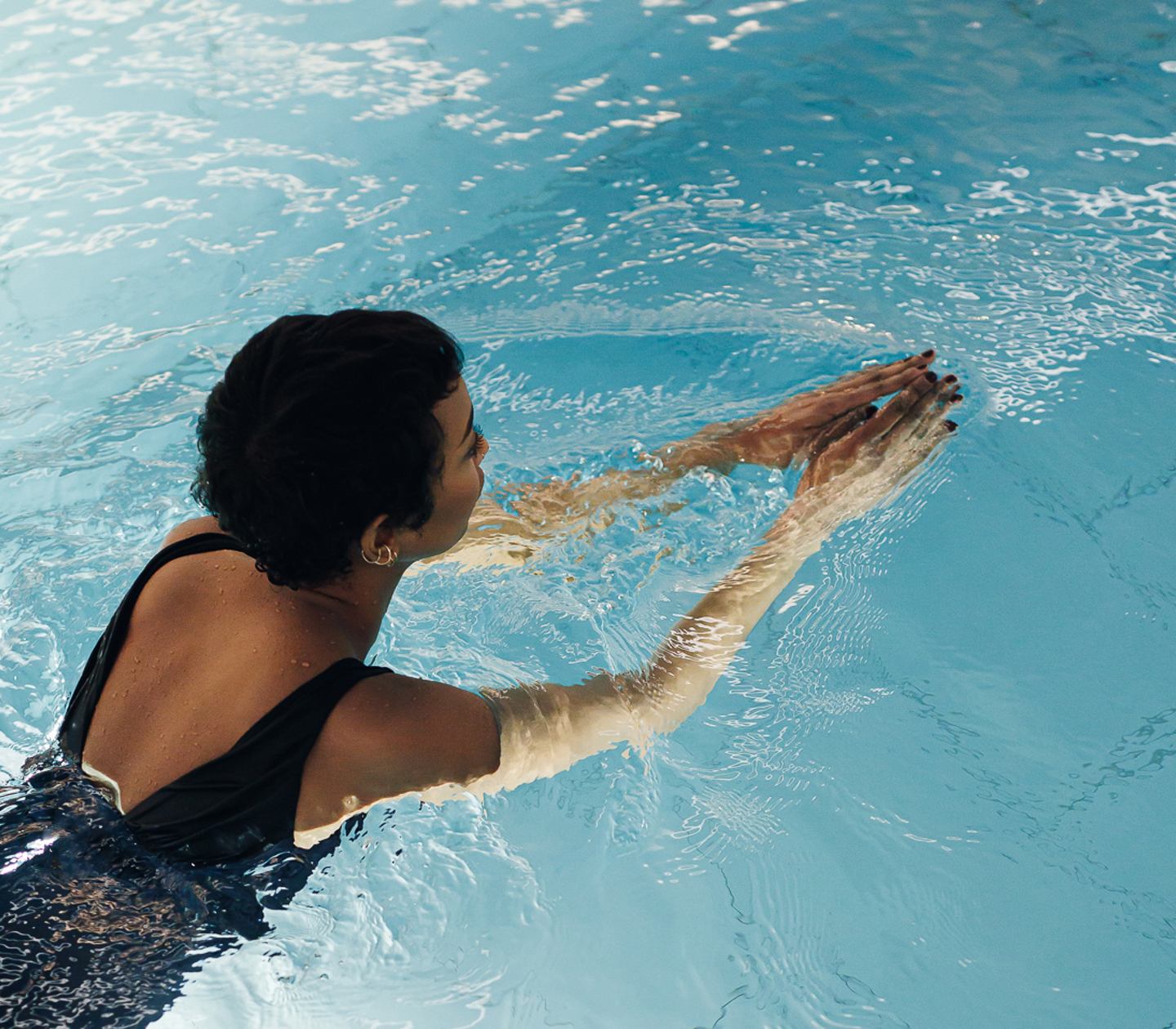 Kvinna i svart baddräkt som simmar i pool