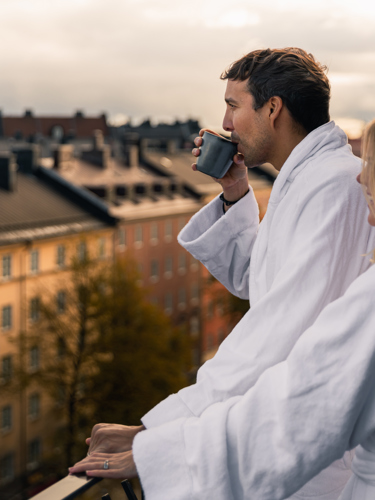 Par i morgonrockar som blickar ut över Stockholms takåsar