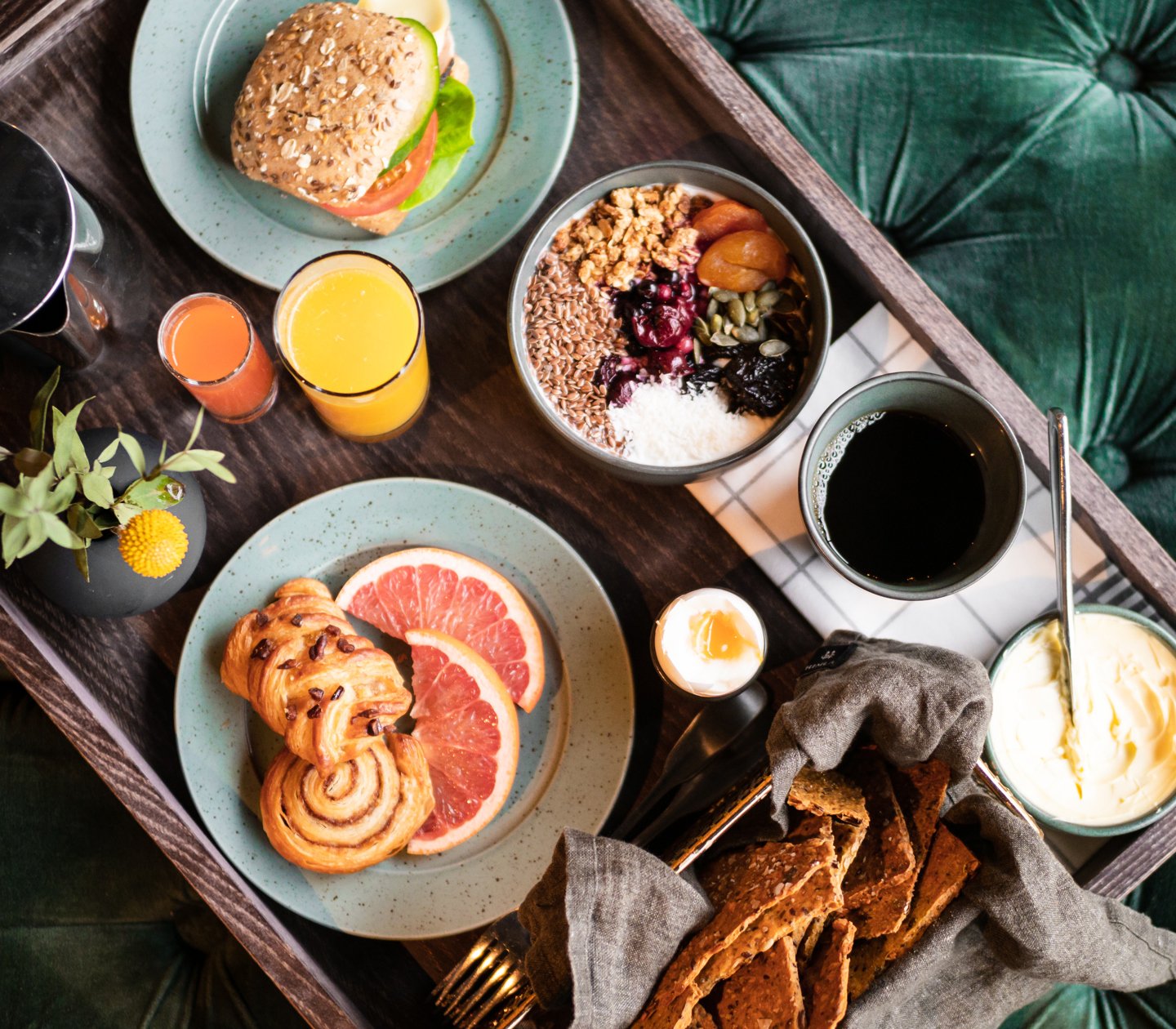 Frukostbricka på grönt tyg med smörgåsar, kaffe och frukt