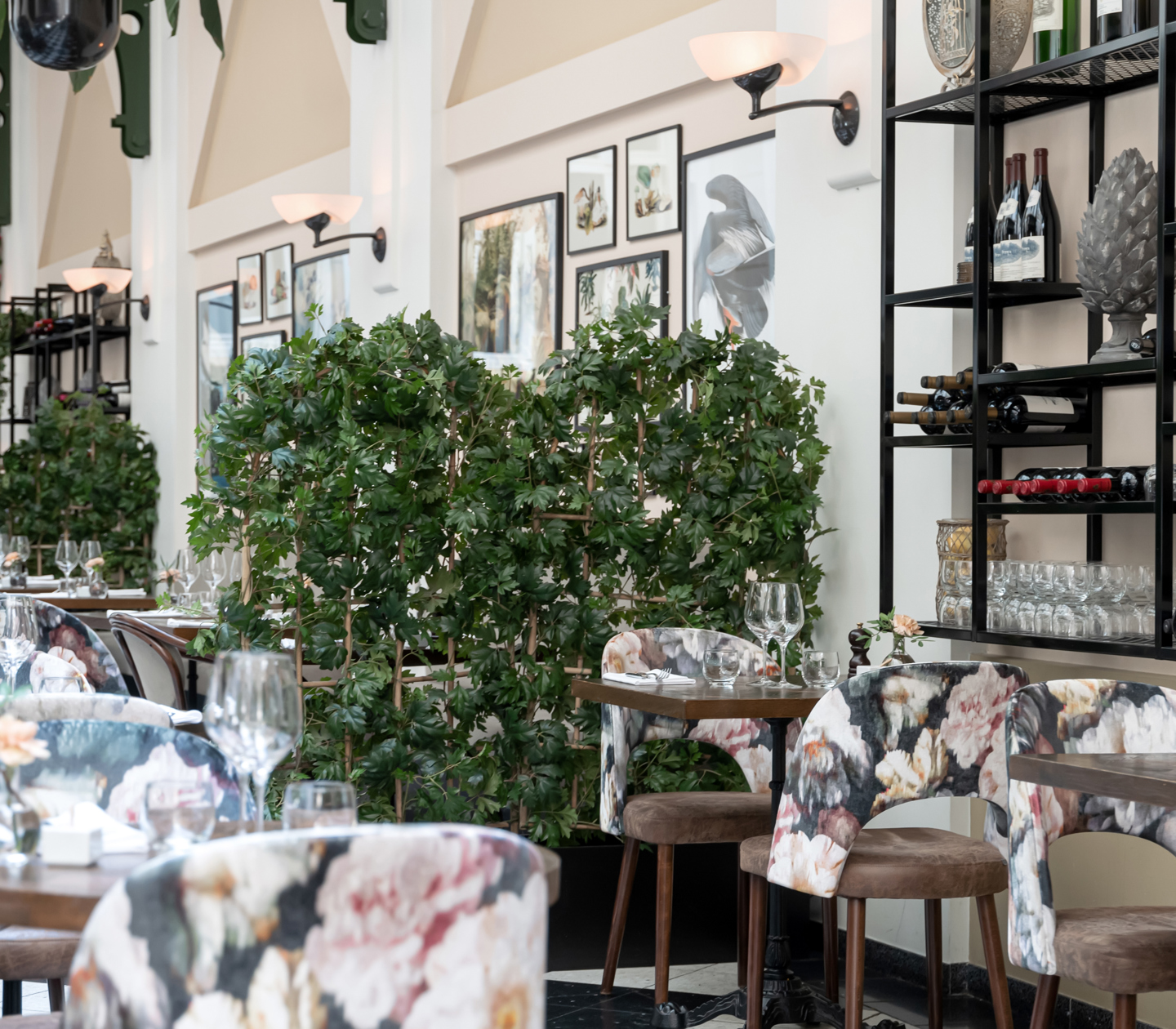 Elegant restaurangmiljö med dukade bord, växter, viner och tavlor