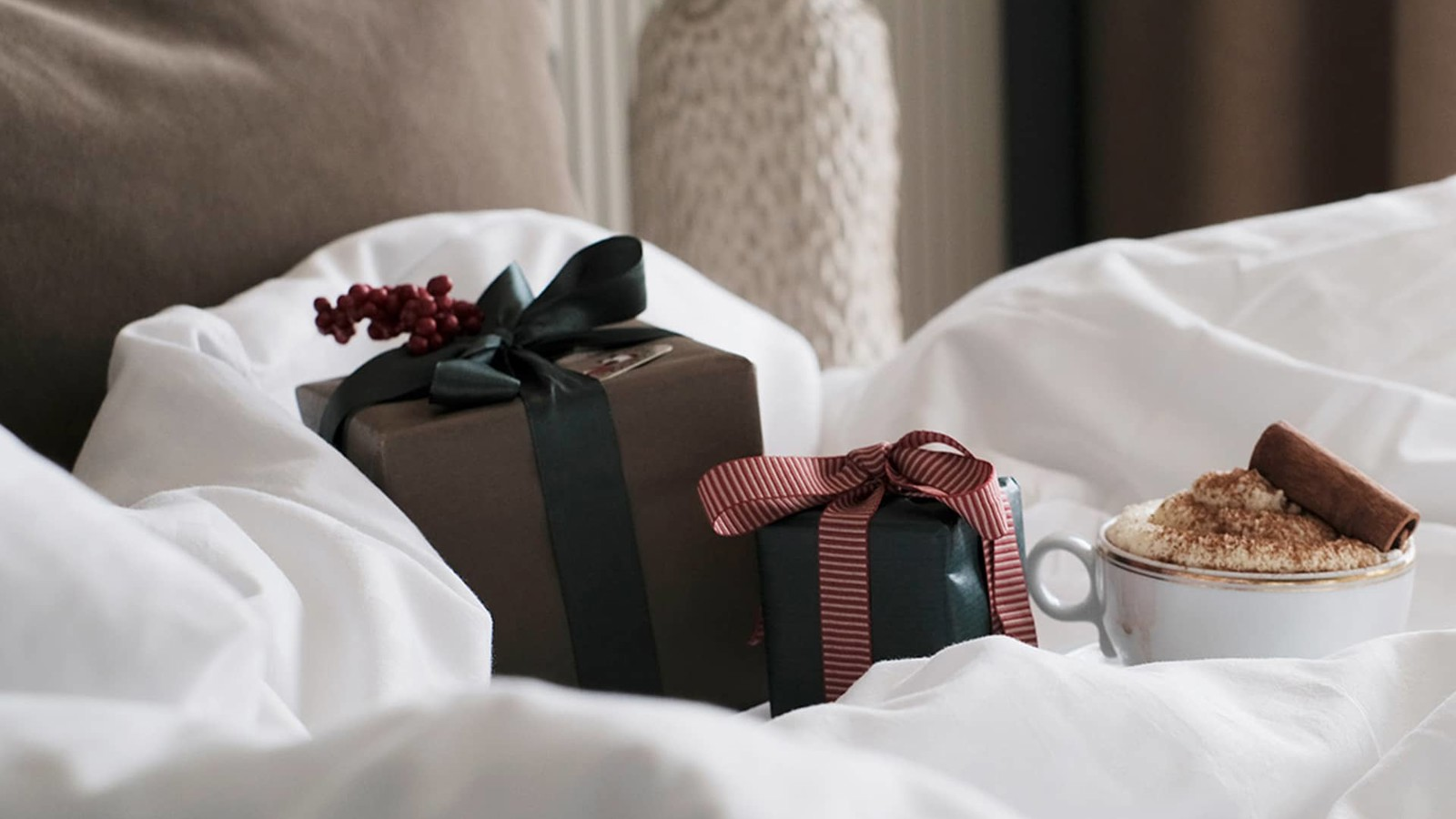 Julklappar och en kopp varm choklad på en fluffig hotell säng