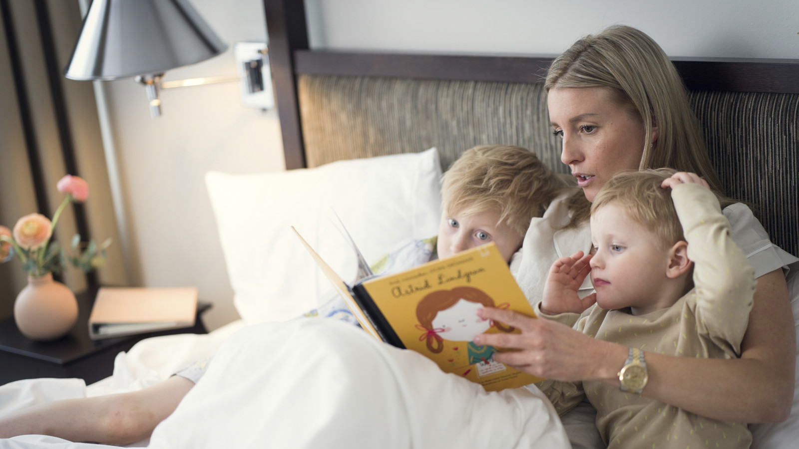 Kvinna läser bok för två barn i en säng