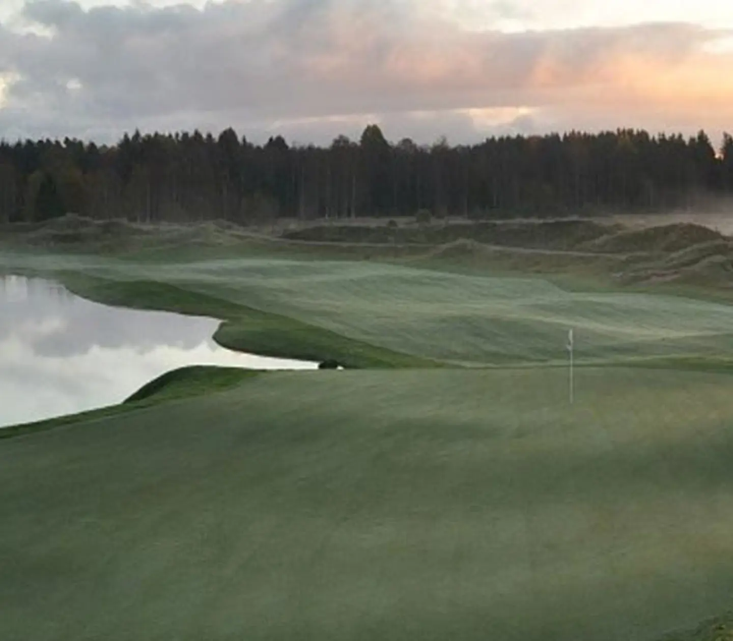 En golfbana omringad med kullar och skog