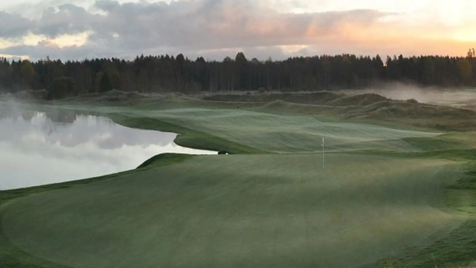 En golfbana omringad med kullar och skog
