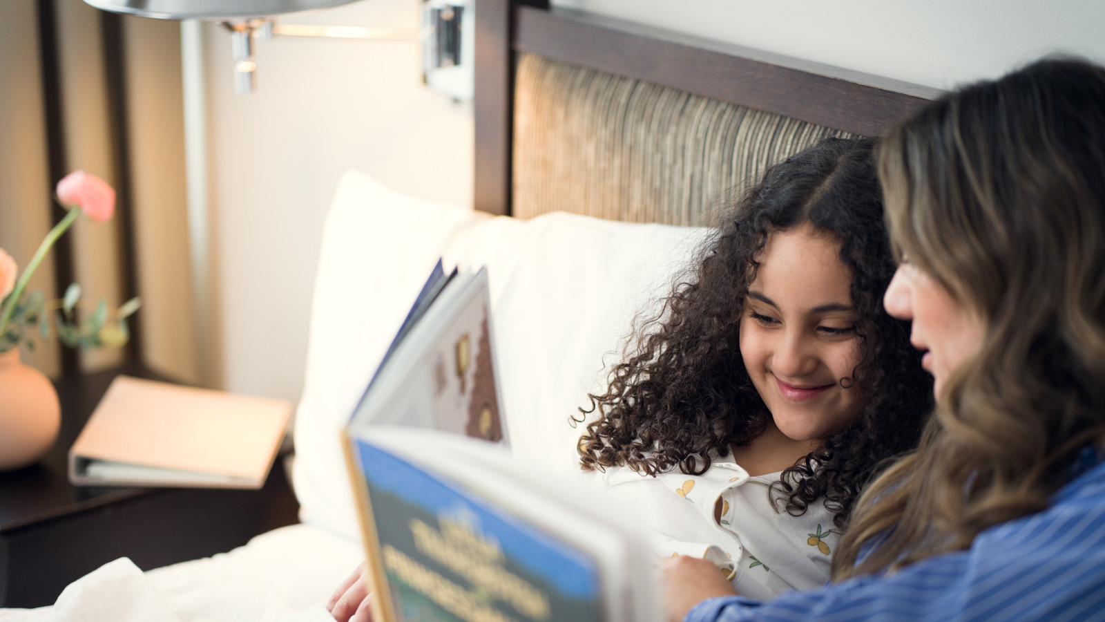En familj tillsammans på en hotellsäng som läser en bok