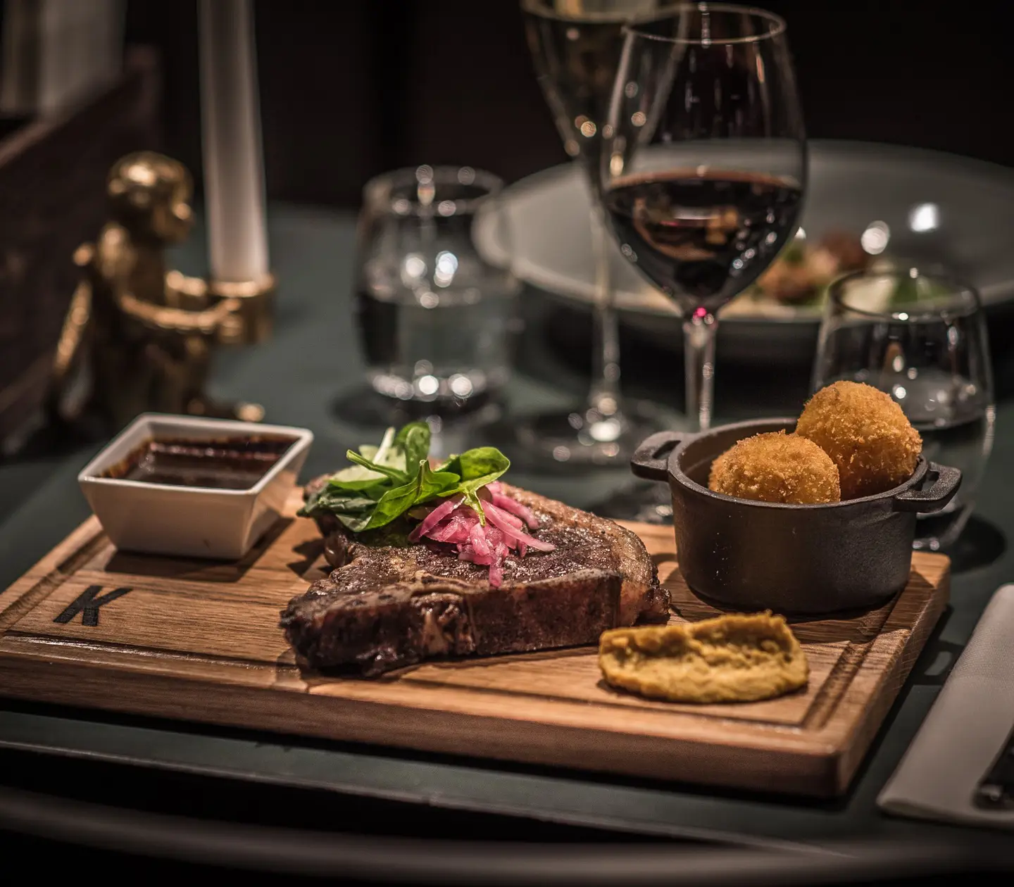 Exklusiv middag med stek och sås på träbricka, serverad med vin och tillbehör