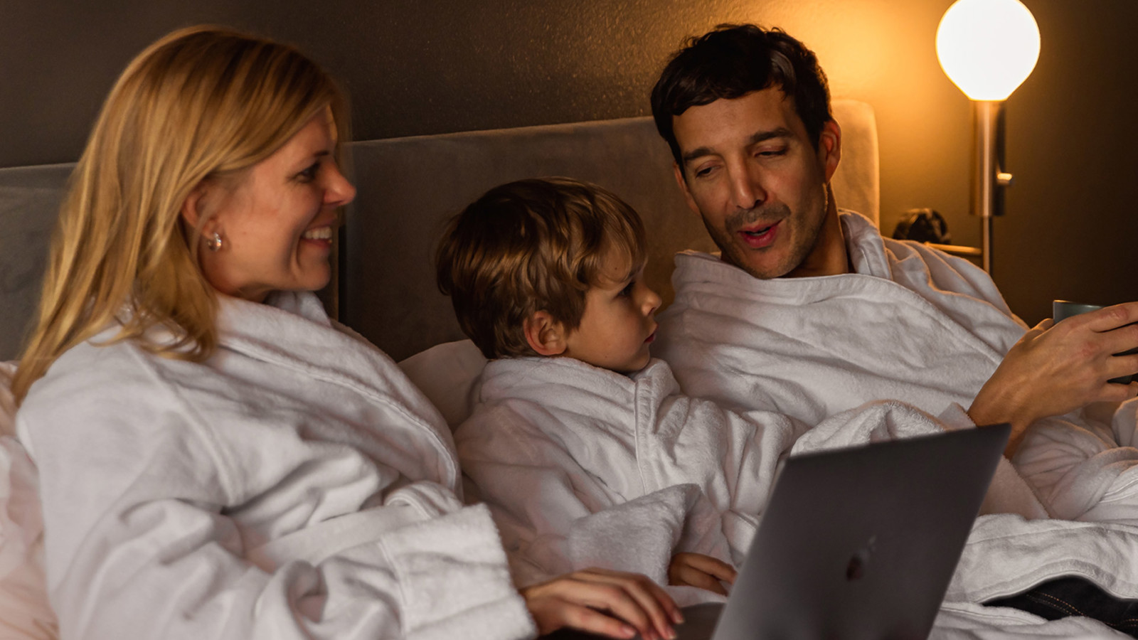 Skrattande familj i hotellsäng på Elite Stadshotellet i Luleå