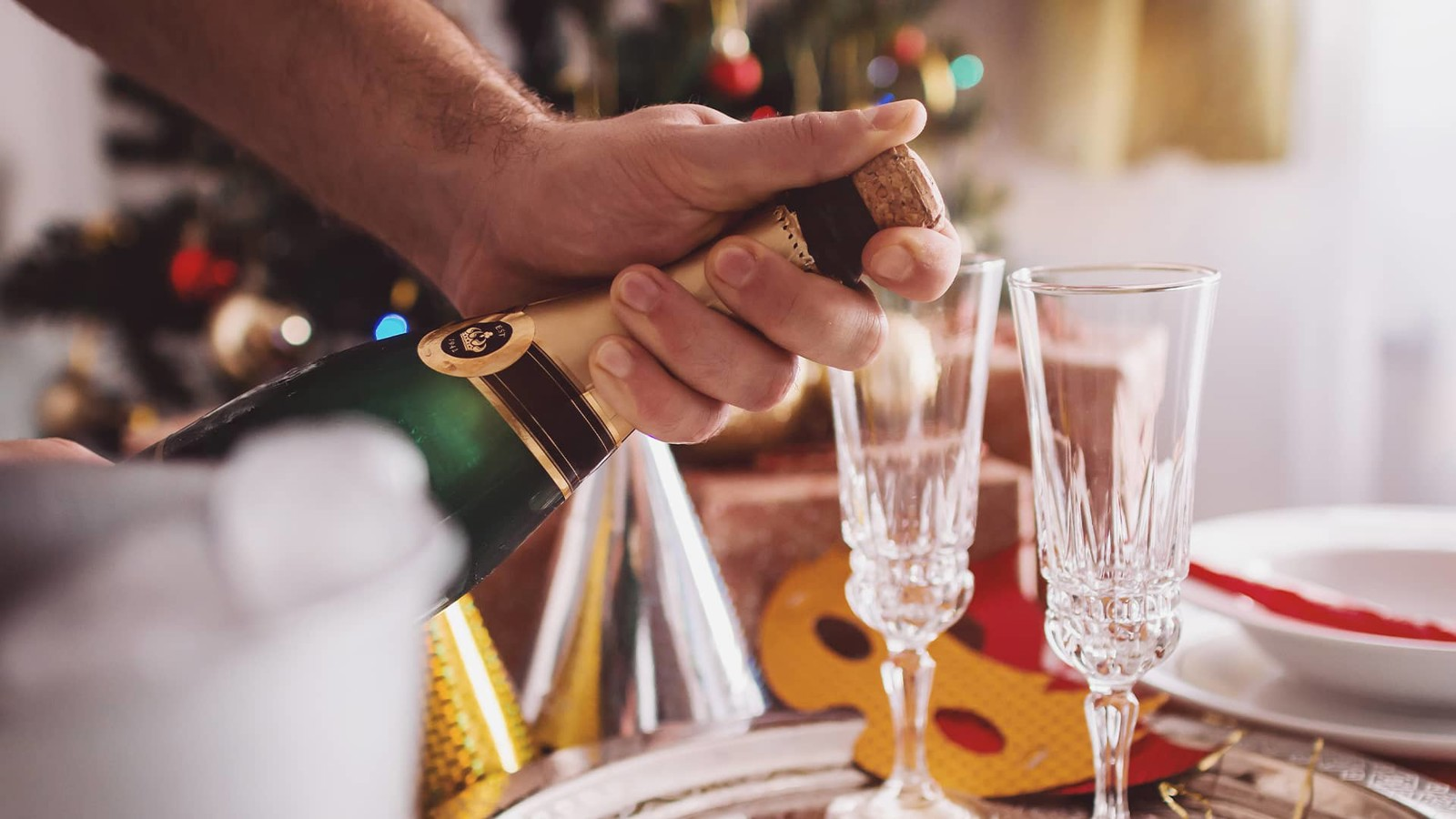 Två champagneglas och champagneflaska med nyårs accessoarer i bakgrunden