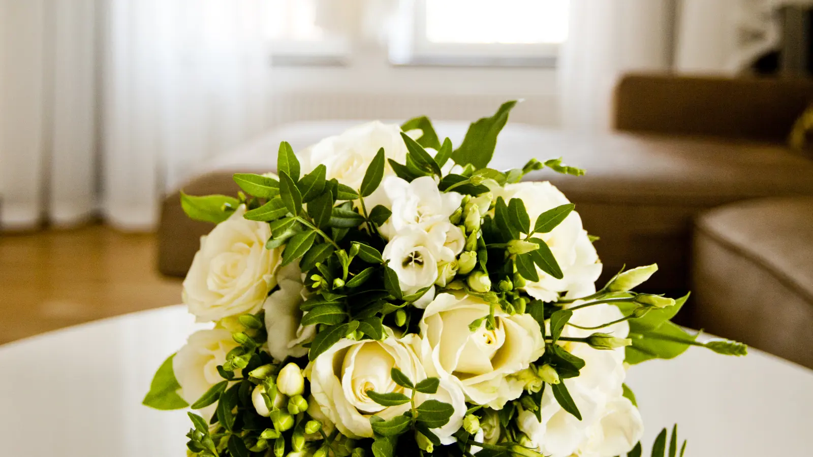 Bröllopsbukett och en bröllopsklänning hängandes i bakgrunden