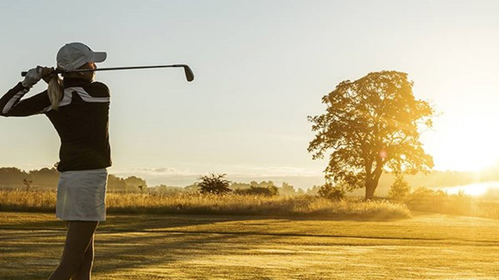 Golfer on a golf course in sunset