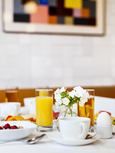 Frukost uppdukad på bord med juice, kaffe och smörgås